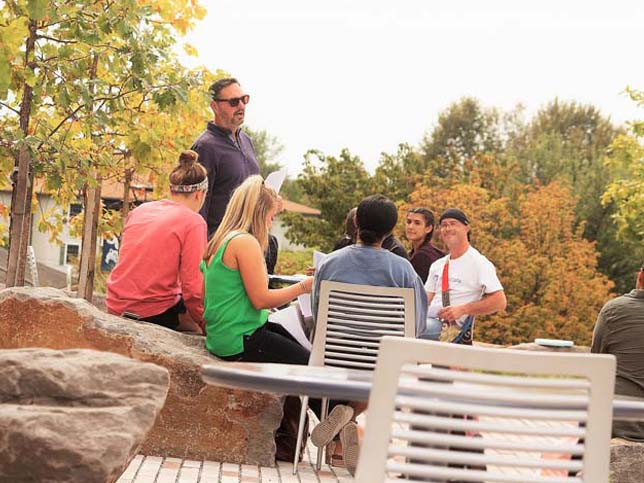 A Scranton faculty member teaches a group of students outside on the patio of the Study Learning Center.