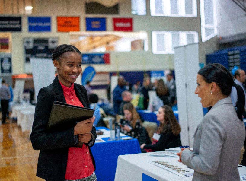 A student talks to a potential employer at Penn State Abington’s annual job fair in the Athletic Building