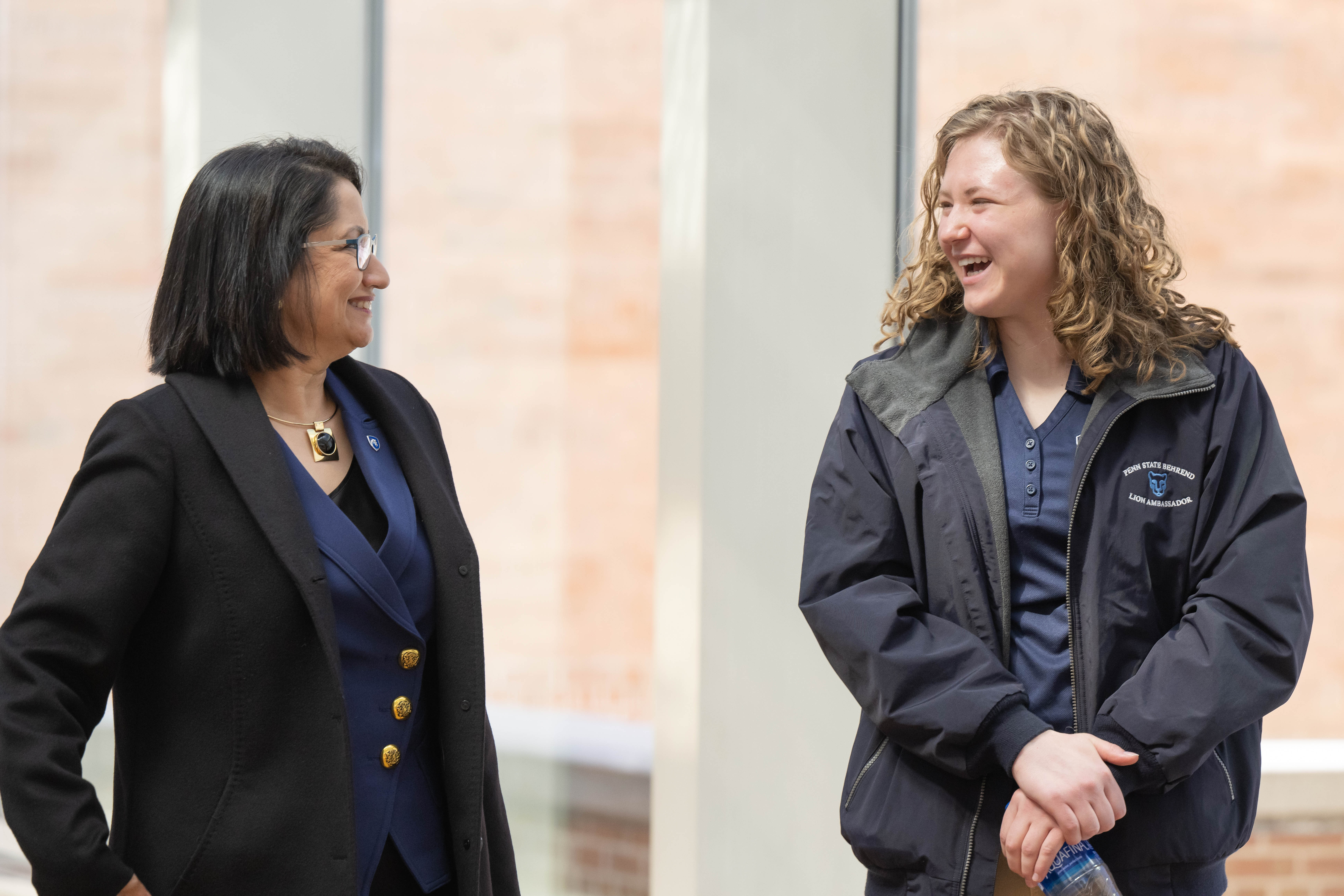 Neeli Bendapudi stands next to a female college student as they engage in conversation and laugh.