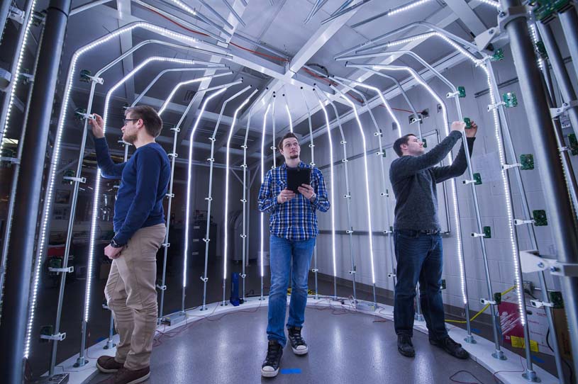 Three male students working inside a large-scale 3D scanner in Behrend’s Innovation Commons