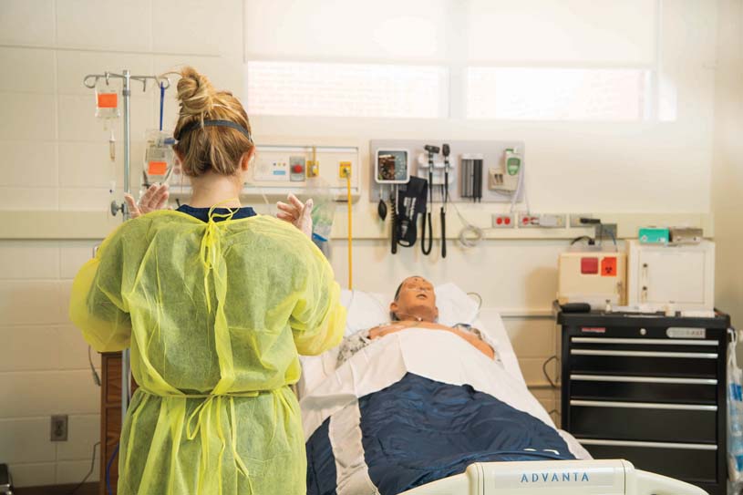 A nursing student preparing to do a simulated exam on a mannequin