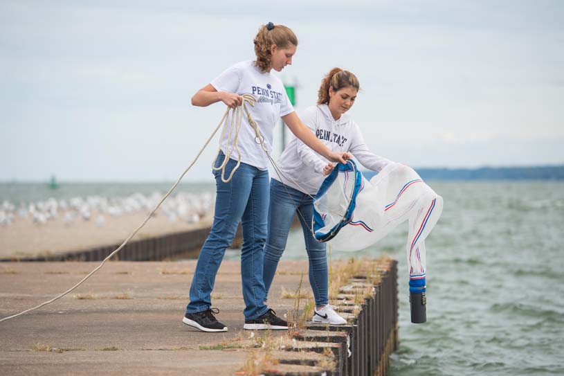 Two female students casting a net into Presque Isle Bay