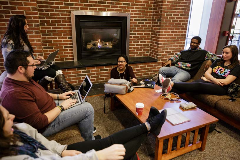 A group of students study and talk in a common area beside a fireplace on the Penn State Berks campus.