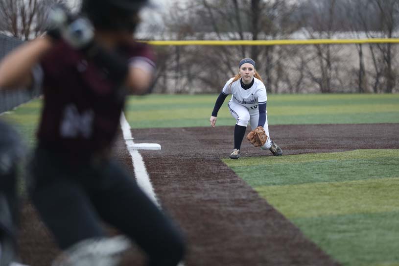 with the batter at homep late in the foreground, a member of the Penn State Brandywine softball team fields a ball at third base.