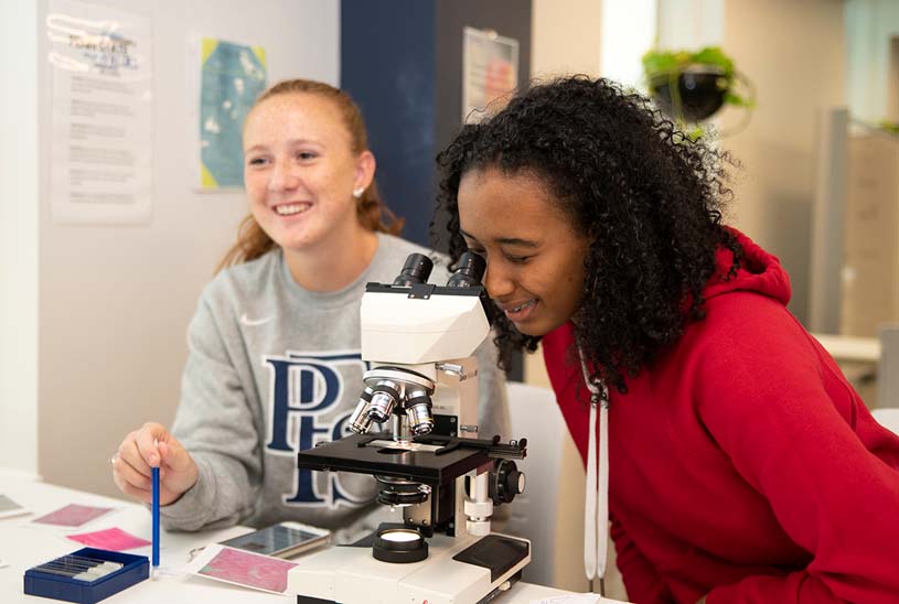 Two students using a microscope in the Penn State Fayette Student Success Center.
