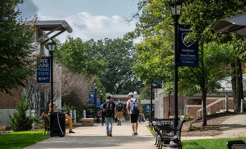 Students walking along campus mall on sunny day at Penn State Hazleton.