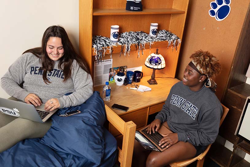 Two students on their laptops inside a room in a Penn State Hazleton residence hall.