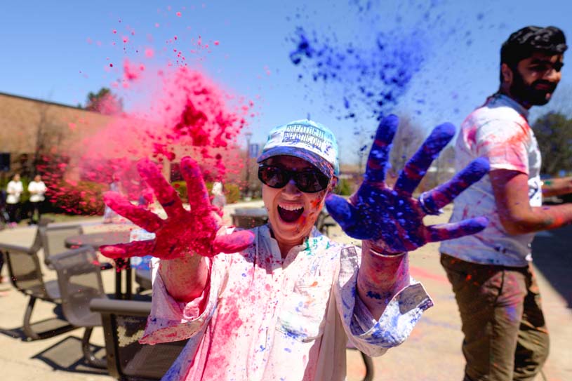 A Penn State Scranton student shows off her multi-colored hands and attire after participating in the Hindu holiday of Holi, the Festival of Colors.