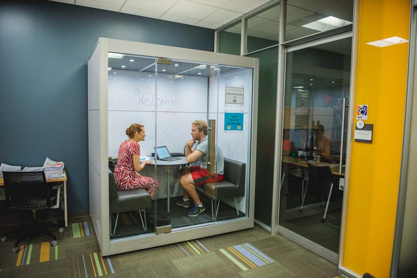 Two students talk while seated in study pods in the David and Ann Hawk Student Success Center at Penn State Scranton.