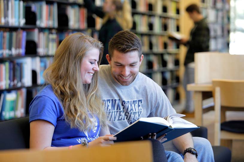 Two students reading a book in the library