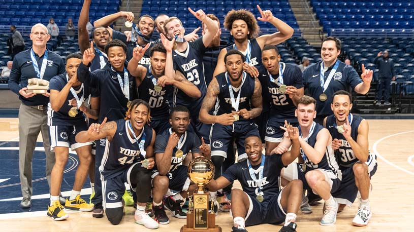 Penn State York Men’s Basketball team pose for a photo while showing off their championship trophy.