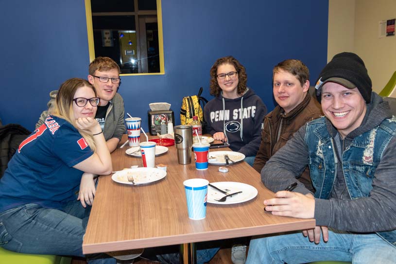 York students seated around a table smiling and enjoying a late-night breakfast during finals week.