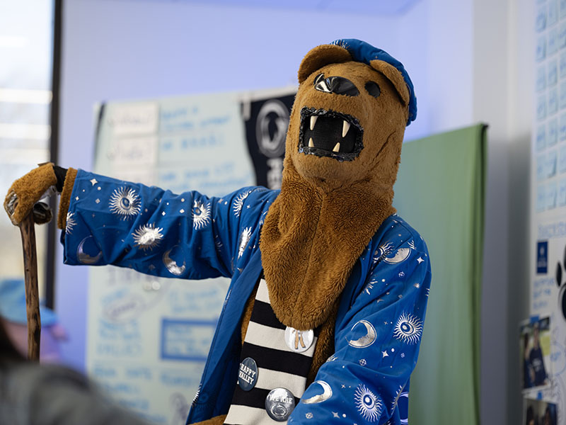 Nittany Lion Mascot dressed in a blue wizard outfit and holding a walking stick. 