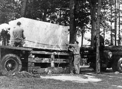 The Indiana limestone block for the Nittany Lion Shrine is unloaded off of the truck and onto a wooden platform.