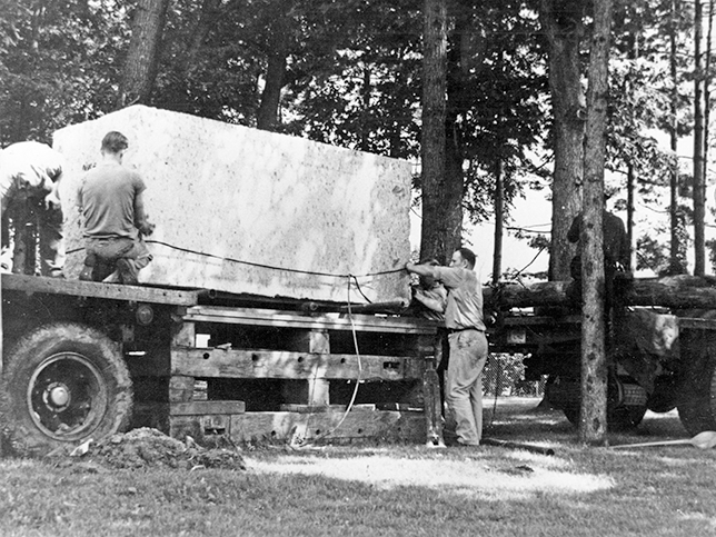 The Indiana limestone block for the Nittany Lion Shrine is unloaded off of the truck and onto a wooden platform.