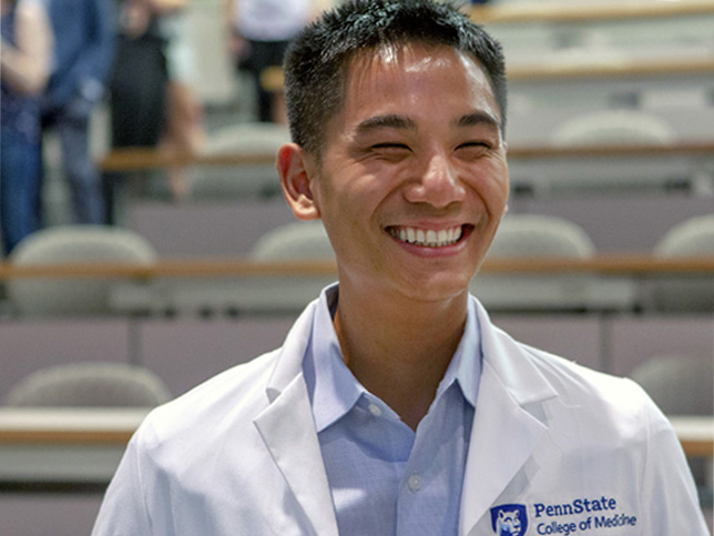 Smiling College of Medicine student with white lab coat.