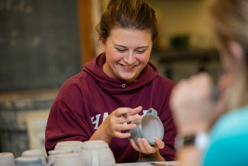 A Shenango student laughs while wiping away extra clay from a mug she is crafting.